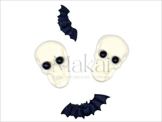 Two edible skull toppers with black eyes and three black bat shapes – Halloween cake decorations
