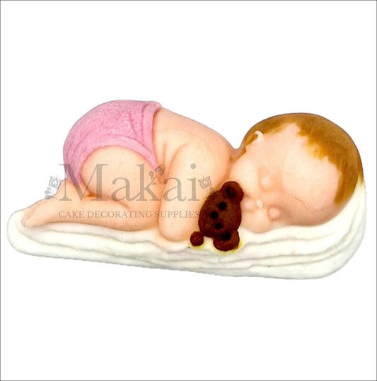 Sleeping baby girl with pink nappy hugging teddy bear cake topper.