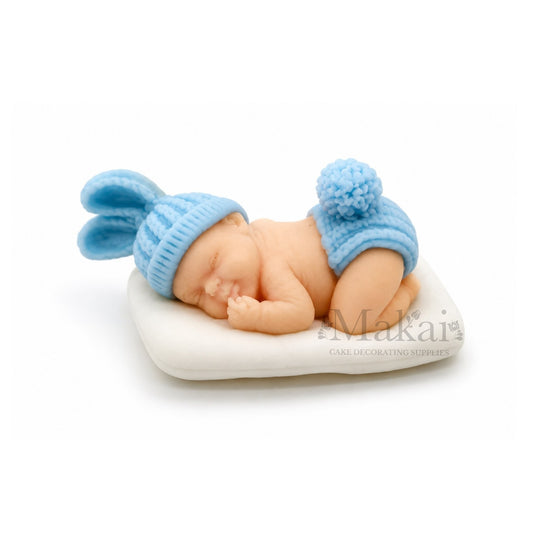 Sleeping baby boy fondant cake topper with blue bunny hat on white cushion