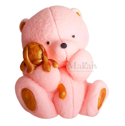 Pink teddy bear holding a small gold bunny, cake topper decoration on a white background