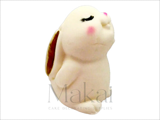 White fondant bunny looking up with gold-painted inner ears and long floppy ears folded backward.